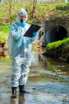 environmental scientist with a walkie-talkie and a notebook on the background of a sewer pipe