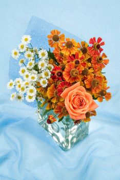 Glass vase with a bouquet of flowers on a fabric background