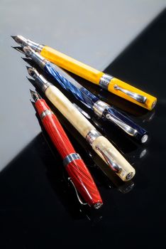 Four different pens on a glass background with highlight