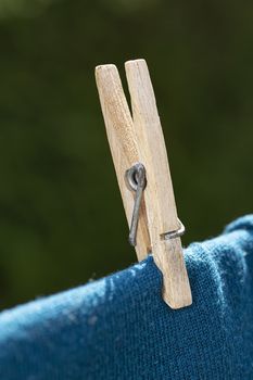 close up of a wood clothesline pin hold a black shirt on a line