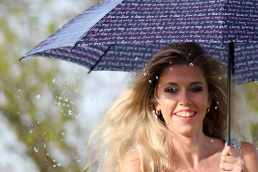 smiling blonde girl in the dress with umbrella, rainy weather.