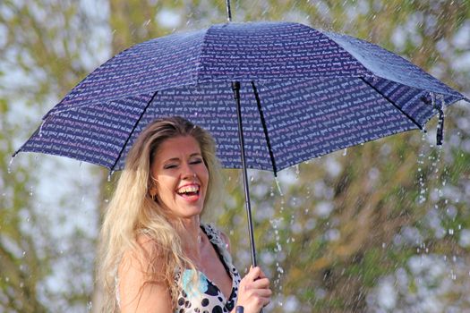 smiling blonde girl in the dress with umbrella, rainy weather.