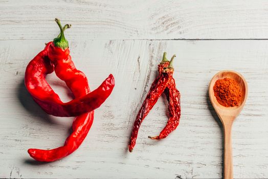 Fresh, dried and ground red chili pepper over colored wooden background.