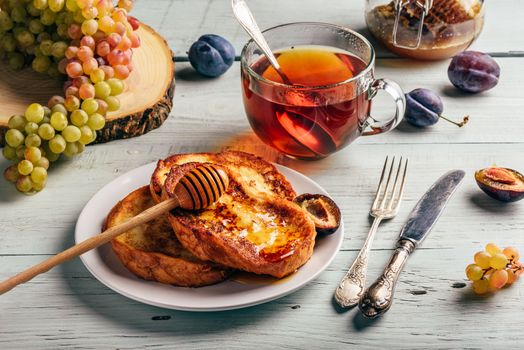 Healthy breakfast concept. French toasts with honey, fruits and tea over white wooden background