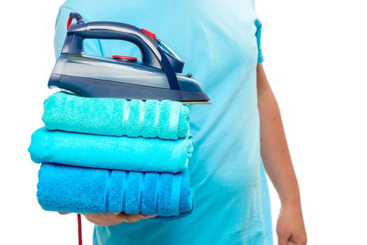 iron and a stack of ironed terry towels in male hands close-up