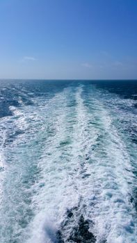 White foamy Jet behind the vessel on a background of blue sea.