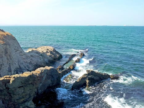 view of the rocky coast. Surf hits the rocks. Summer sunny day.