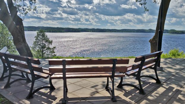 A lonely bench overlooking the lake, on a summer sunny day