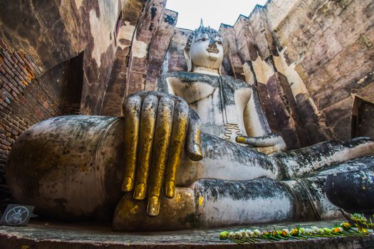 Sukhothai Historical Park, Thailand, traveller with ancient Buddha statue at Wat Si Chum temple.