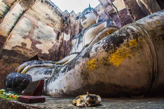 Sukhothai Historical Park, Thailand, traveller with ancient Buddha statue at Wat Si Chum temple.