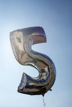 number 5 helium filled balloon against a blue sky