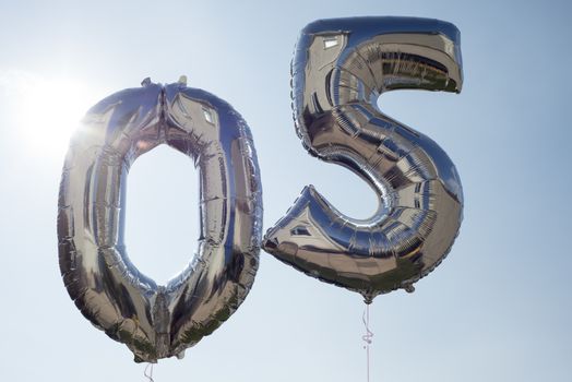 numbers 0 and 5 helium filled balloons against a blue sky