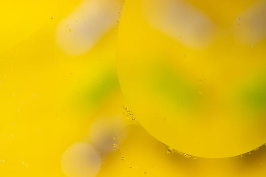 Abstract oil spots on water on blurred yellow background. Photo with small depth of field.