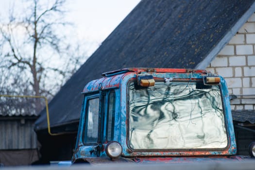 Blue and red tractor roof with the glass in the village yard.