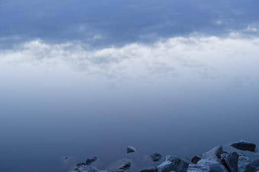 Gray evening sunset above the lake or river. Blue clouds on horizon. Abstract picture.