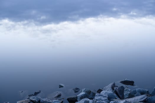 Gray evening sunset above the lake or river. Blue clouds on horizon. Abstract picture.