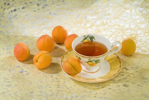 Cup of tea and apricots on a fabric studio background