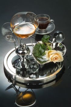 Cup of coffee and glass of cognac on a glass background