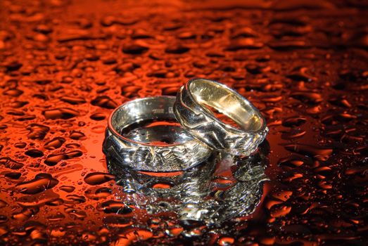 Wedding rings and rose petals on a studio background