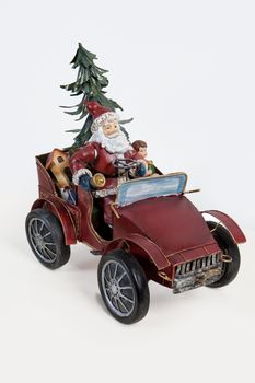 Statuette of Santa Klaus sitting in an old car on isolated background