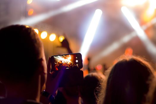 Shooting or streaming concert on smartphone. Online broadcast event, video recording dance party