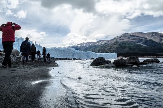 Some people walking near the shore to the Perito Moreno glacier front