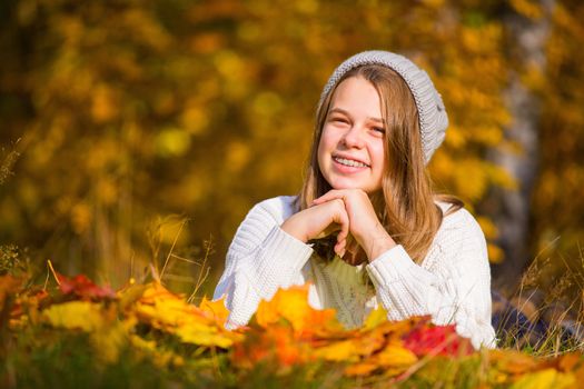 Portrait of pretty nice teenage girl with dental braces in autumn park , background with copy space for text