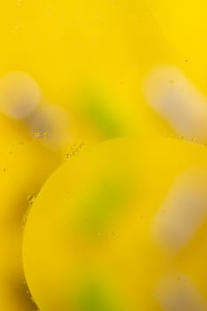 Abstract oil spots on water on blurred yellow background. Photo with small depth of field.