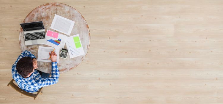 Office workspace top view. Businessman working at wooden desk, using laptop and financial reports , copy space for text