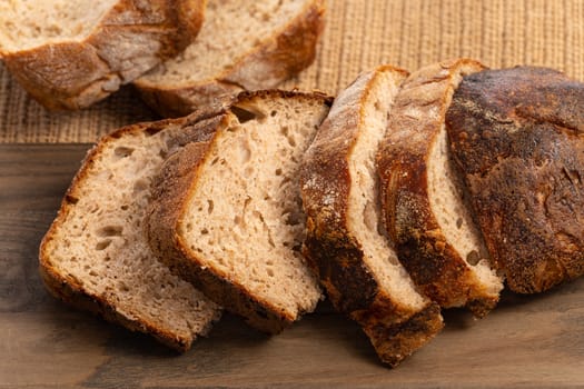 Close up of hearty artisan sourdough bread slices on a wood board.