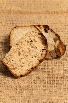 Close up of hearty artisan sourdough bread slices on jute fabric.