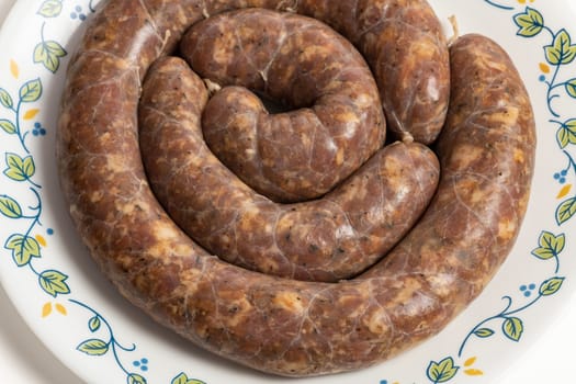 Homemade stuffed pork sausages in a a plate isolated on white.