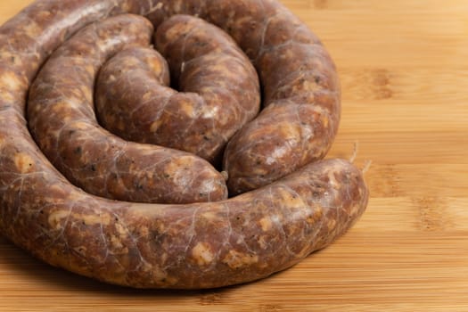 Raw homemade stuffed pork sausages isolated on a woodboard.