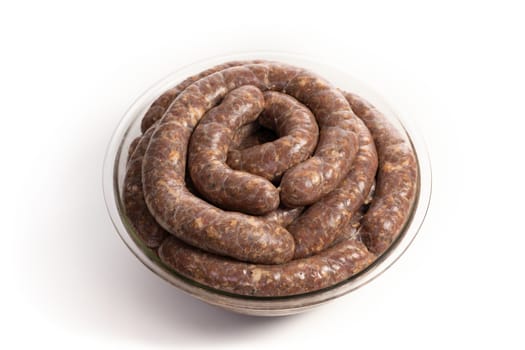 Homemade stuffed pork sausages in a glass bowl isolated on a white background, with copyspace.