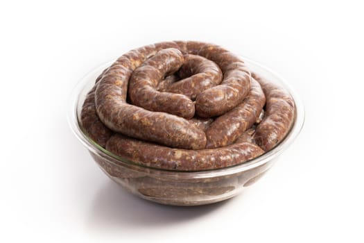 Homemade stuffed pork sausages in a glass bowl isolated on a white background, with copyspace.