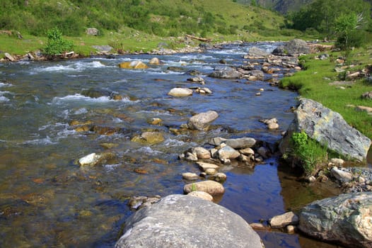 The rocky shore of the mountain river Sema and the rapid flow of the stream. Altai, Siberia, Russia.