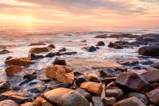 Coastal views of peaceful waves and stoney shores with misty morning light