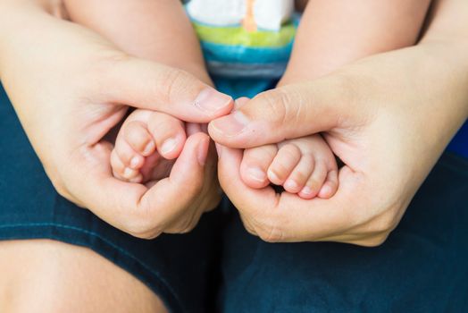 Baby feet in mother's hands, concept of love and family,sensitive focus