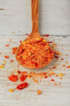 Spoonful of crushed red chili pepper over wooden background