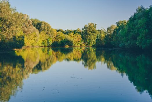 Blue lake in the autumn forest at sunset.