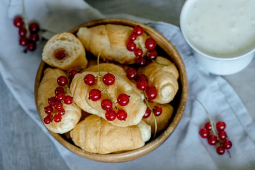 Croissants with currant berries on a wooden tray. The concept of a wholesome breakfast