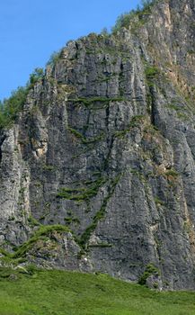 Steep high cliff overgrown with small grass, Shaman Mountain, a sacral place in the Altai Mountains. Siberia, Russia.