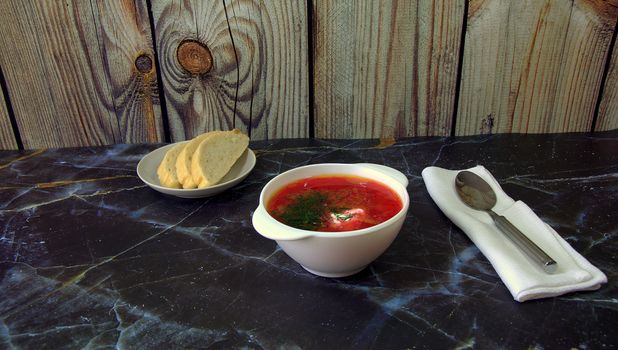 Russian national soup Borsch spoon on a napkin spoon and saucer with bread.