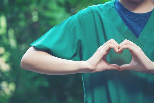 women making heart shapes with their hands on nature green background