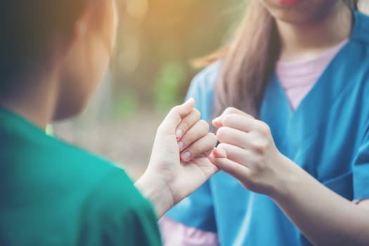 hands hook each other's little finger on nature background, concept of promise 