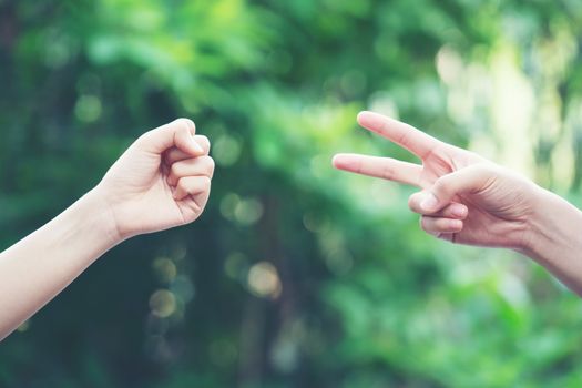 Couple play rock paper scissors hand game nature green background