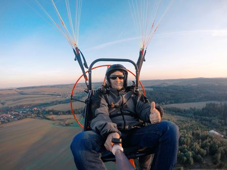 Powered paragliding tandem flight, man taking selfie with action camera