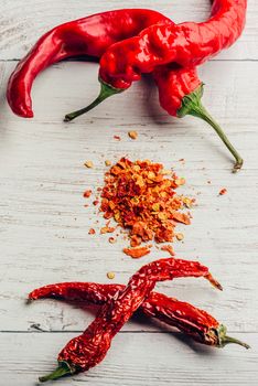 Fresh, dried and crushed red chili pepper over white wooden background.