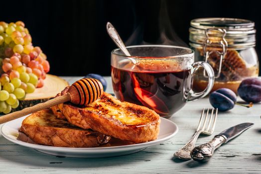 Healthy breakfast concept. French toasts with honey, fruits and tea over white wooden background