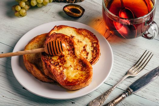 Healthy breakfast concept. French toasts with honey, fruits and tea over white wooden background